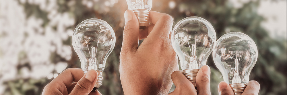 Fachkraft Heizung, solar energy concept hand group holding light bulb in nature